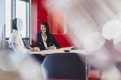 Man and woman talking in an office. China. Primary color: red.