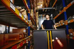 male in elevator between distrubtion center racks.
