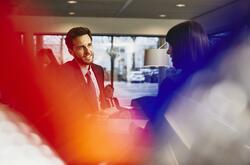 Business man receiving an entrance pass at a reception desk. Primary color: red.