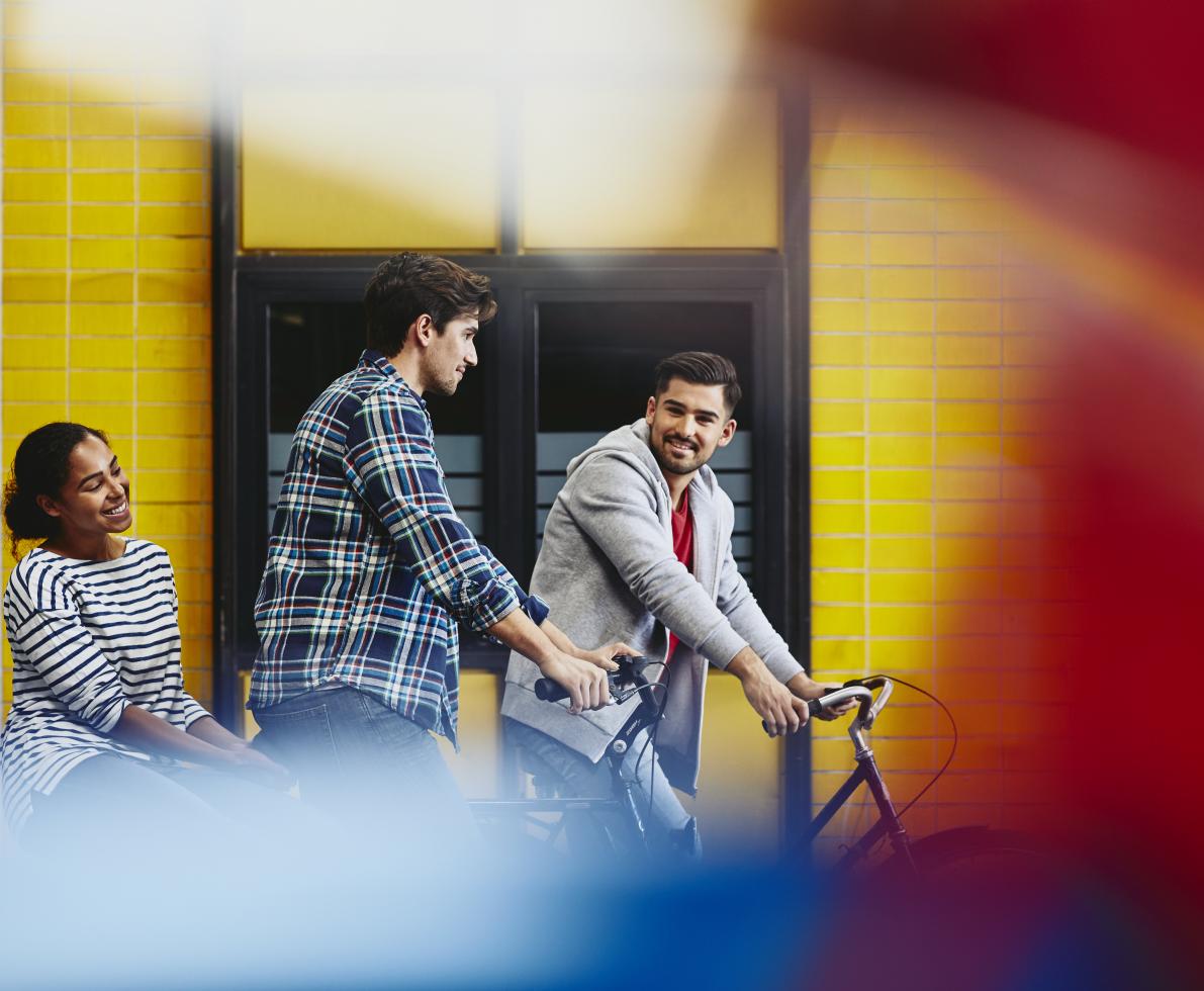 Group of colleagues (two males, one female) leaving work. Bicycle. Two caucasian males. One African-American woman. Checkered shirt and striped T-shirt. Primary color red. Secondary color yellow.