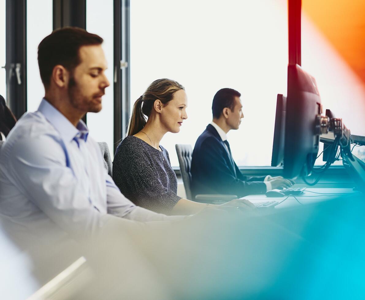 People working in their desks. Primary colors: blue and red.