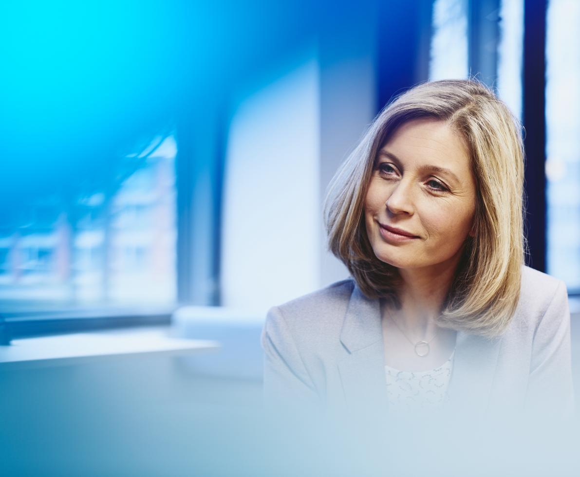 Business woman in an office smiling. Primary color: blue