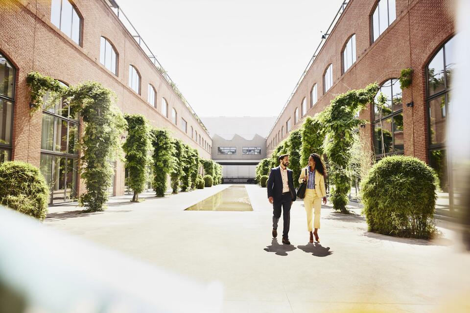 Man and woman walking outside between office buildings.